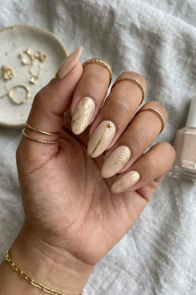 Soft nude nails enhanced with delicate gold details for a classy manicure.