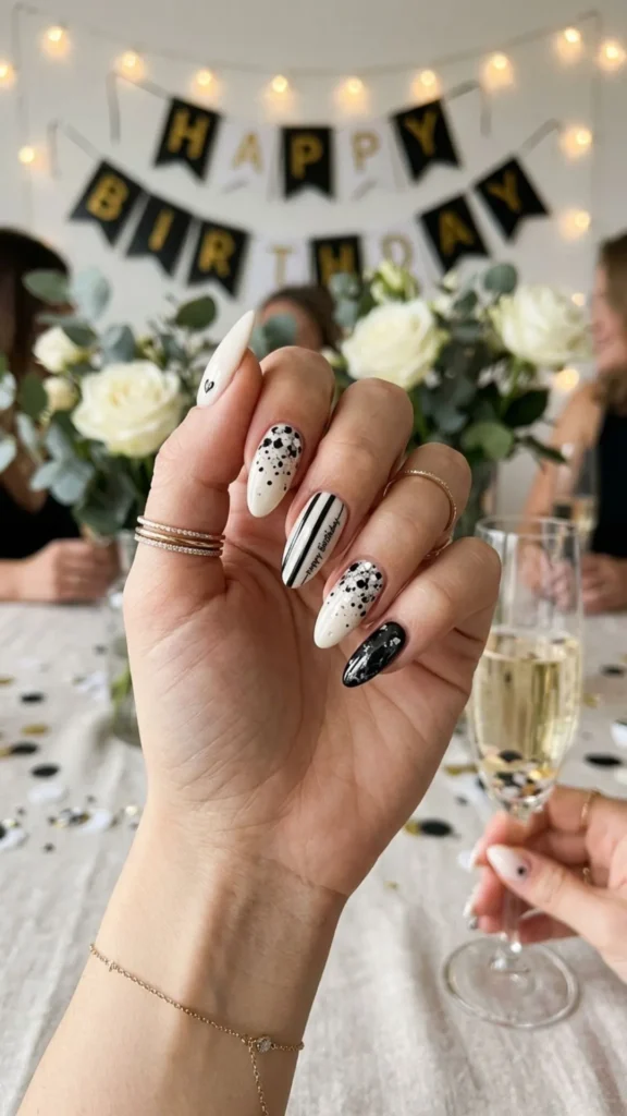 Chic almond birthday nails with black and white confetti.