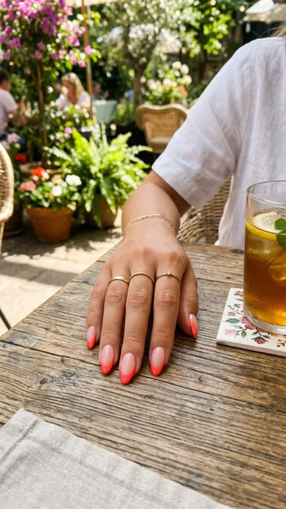 Bright coral French tip nails with a nude base for a vibrant and chic summer look.

