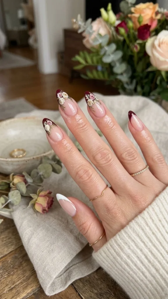 Floral burgundy French nails with delicate botanical accents for an elegant transitional manicure.