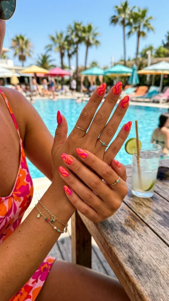 Bold hot pink and orange swirl nails with a retro summer vibe.