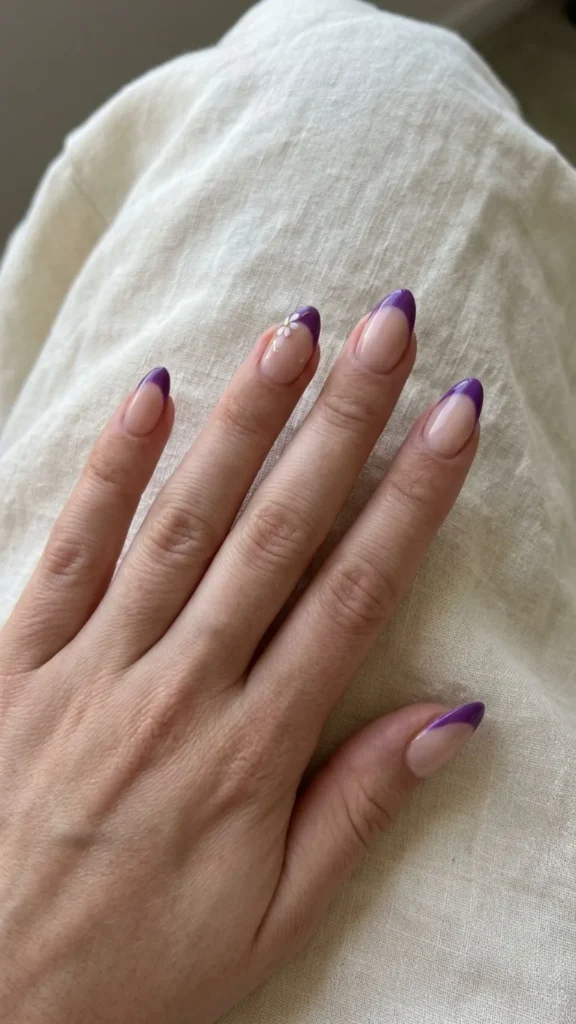 Purple French tip nails decorated with delicate flowers for a pretty and feminine seasonal manicure.